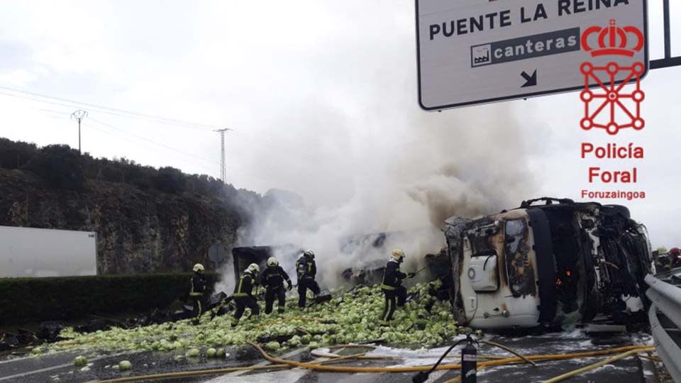 Bomberos sofocando las llamas del camión volcado en la Ap15